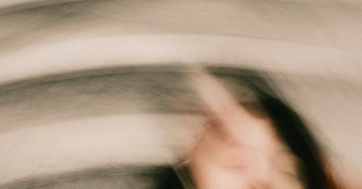 Motion blur of a person turning their head, creating abstract streaks of color and skin tones