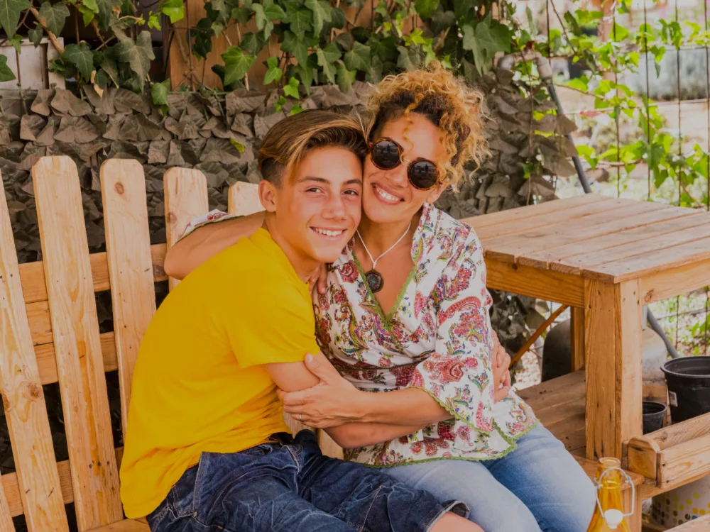 Mother and teenage son sitting together outdoors