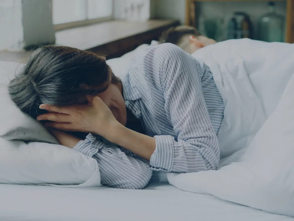 A person in bed looking exhausted.