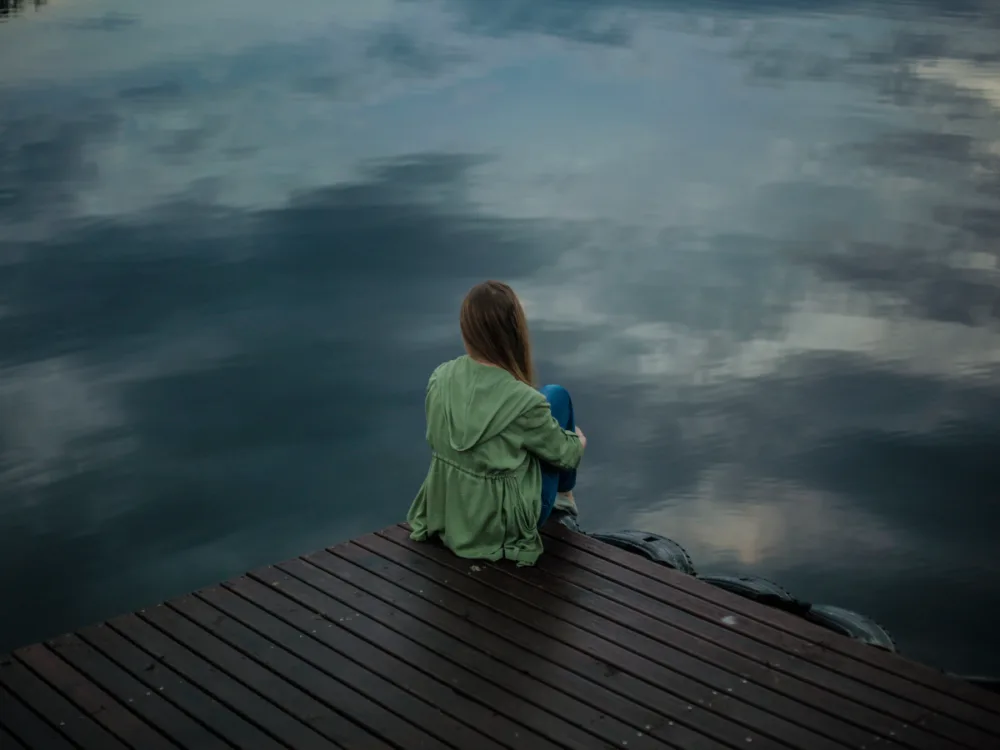 Woman sitting on the edge of a lake