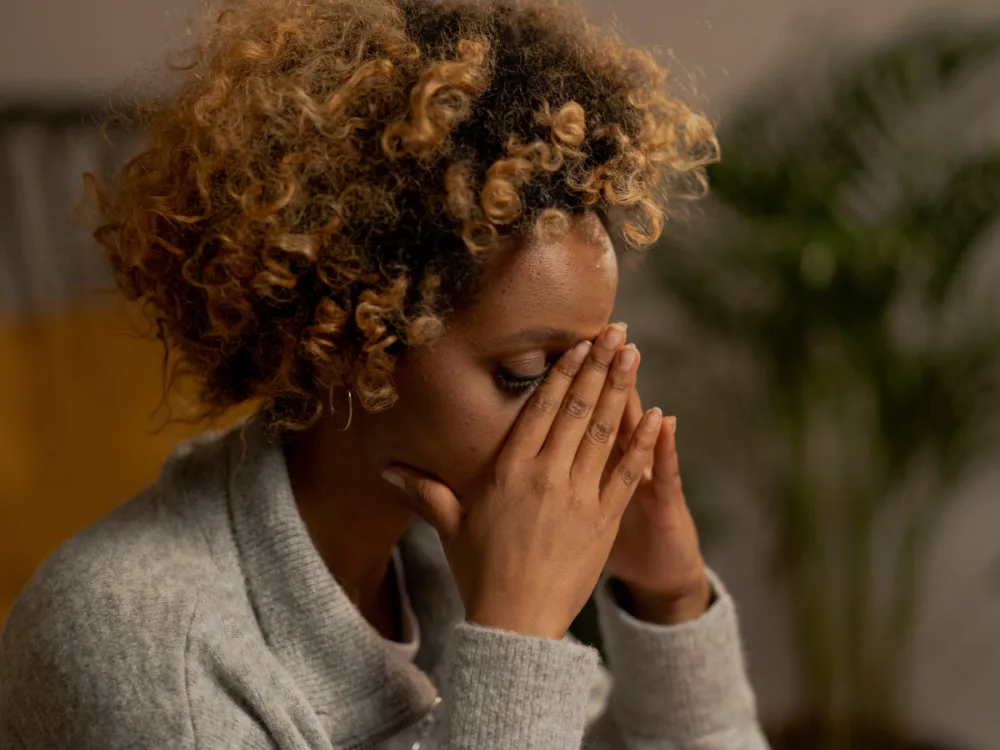 Woman with her hands on her face, seeming tired or sad.