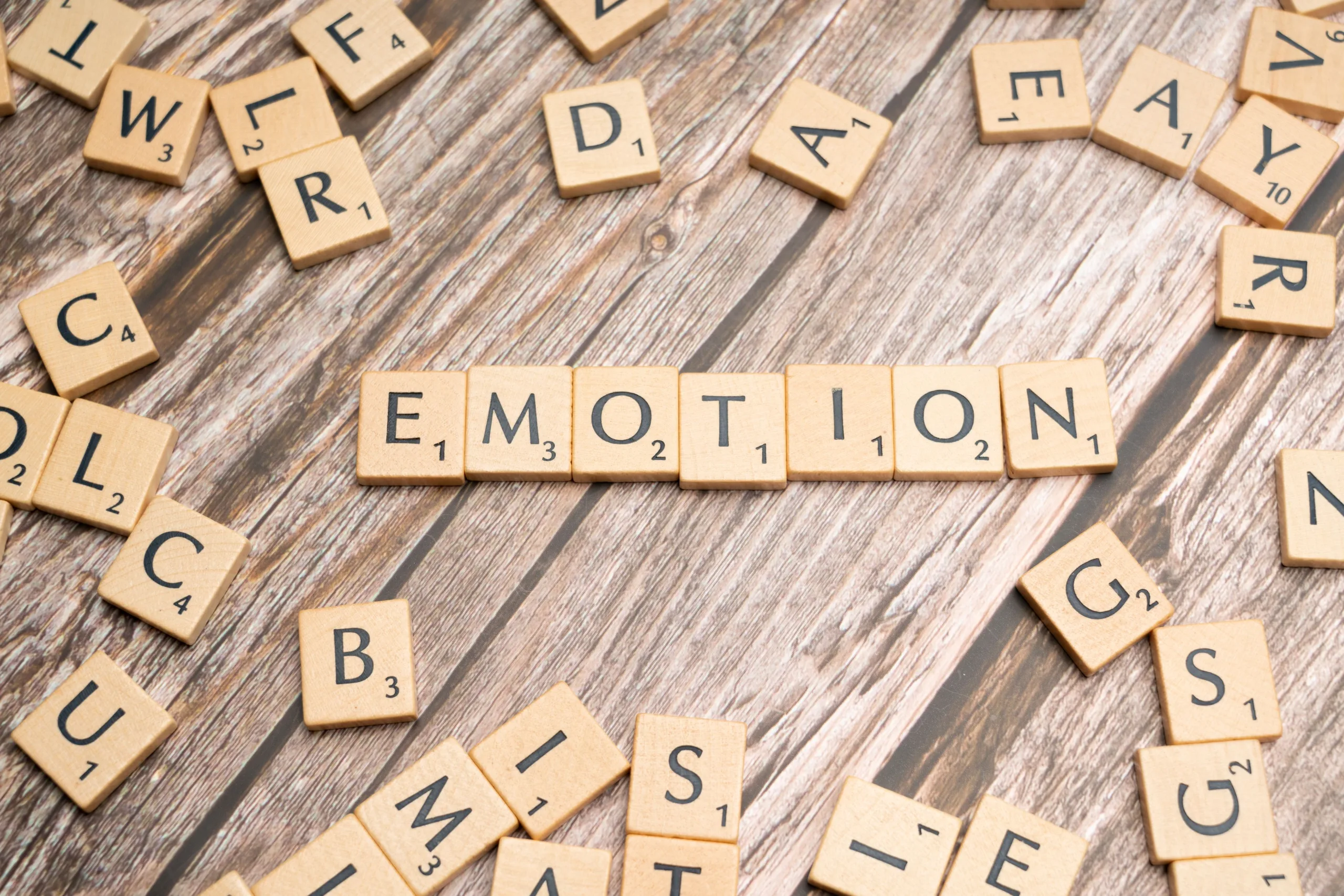 Wooden letter tiles spelling the word emotion on a wooden surface.